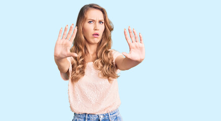 Young beautiful caucasian woman with blond hair wearing casual clothes doing stop gesture with hands palms, angry and frustration expression