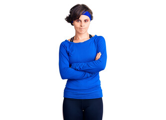 Beautiful young woman with short hair wearing training workout clothes skeptic and nervous, disapproving expression on face with crossed arms. negative person.
