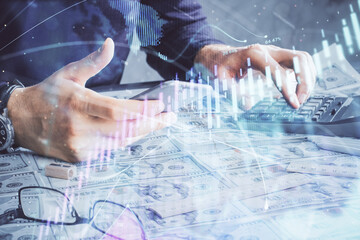 Double exposure of man's hands holding and using a digital device and forex graph drawing. Financial market concept.