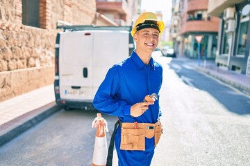 Young hispanic workman smiling happy working at street of city