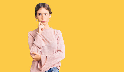 Fototapeta na wymiar Beautiful caucasian woman with blonde hair wearing casual winter sweater serious face thinking about question with hand on chin, thoughtful about confusing idea