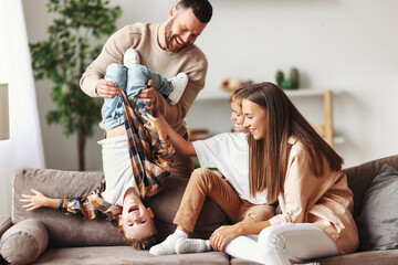 happy family mother father and kids having fun at home on couch .
