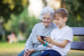 Young boy and his great grandmother watching video on smartphone