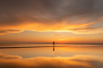 Silhouette of fitness woman running on the beach at sunset. Copy space. 