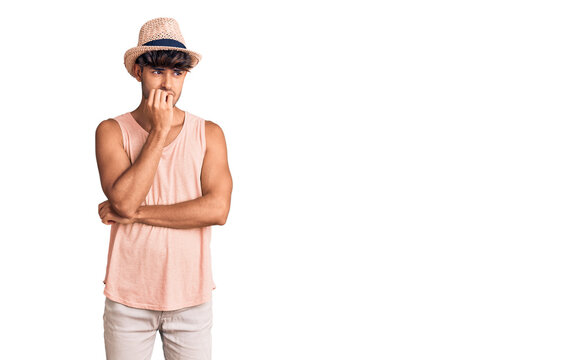 Young hispanic man wearing summer hat looking stressed and nervous with hands on mouth biting nails. anxiety problem.