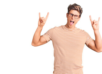 Naklejka premium Young handsome man wearing casual clothes and glasses shouting with crazy expression doing rock symbol with hands up. music star. heavy concept.