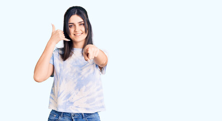 Young beautiful girl wearing casual t shirt smiling doing talking on the telephone gesture and pointing to you. call me.