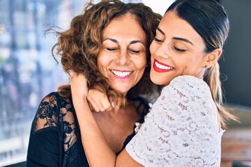 Beautiful mother and daughter smiling happy and confident. Standing with smile on face hugging at...