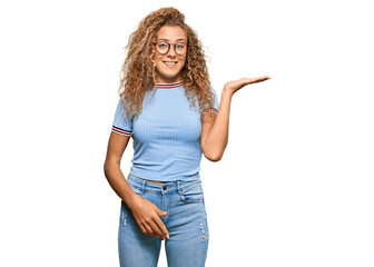 Beautiful caucasian teenager girl wearing casual clothes and glasses smiling cheerful presenting and pointing with palm of hand looking at the camera.