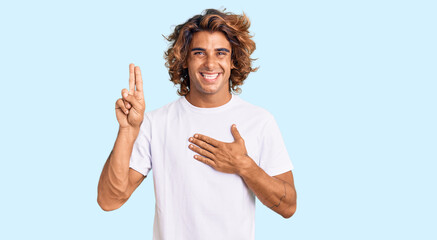 Young hispanic man wearing casual white tshirt smiling swearing with hand on chest and fingers up,...