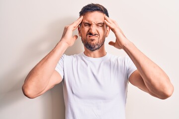 Fototapeta premium Young handsome man wearing casual t-shirt standing over isolated white background with hand on head, headache because stress. Suffering migraine.