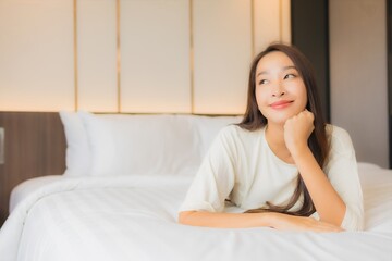 Portrait beautiful young asian woman smile relax on bed in bedroom interior