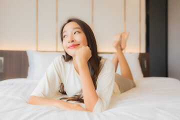 Portrait beautiful young asian woman smile relax on bed in bedroom interior