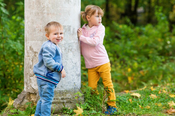 .Children play near the column in the old park on an autumn walk