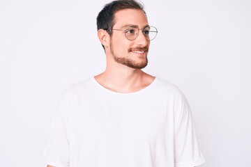 Young handsome man wearing casual clothes and glasses looking to side, relax profile pose with natural face and confident smile.