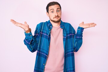 Young handsome man wearing casual clothes clueless and confused expression with arms and hands...