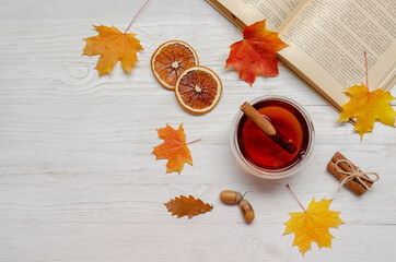 Naklejka na ściany i meble book with tea cup, fall leaves on wooden white background. Top view, flat lay