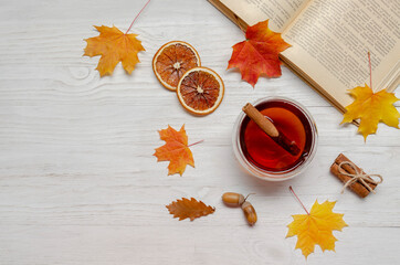 book with tea cup, fall leaves on wooden white background. Top view, flat lay