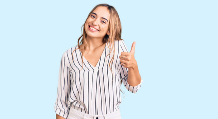 Young beautiful blonde woman wearing casual clothes smiling happy and positive, thumb up doing excellent and approval sign