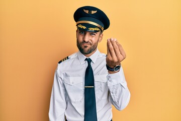 Handsome hispanic man wearing airplane pilot uniform doing italian gesture with hand and fingers confident expression