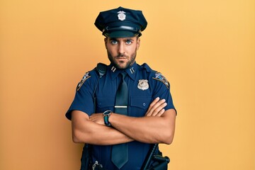 Handsome hispanic man wearing police uniform skeptic and nervous, disapproving expression on face with crossed arms. negative person.