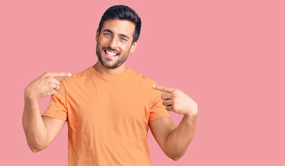 Young hispanic man wearing casual clothes looking confident with smile on face, pointing oneself...