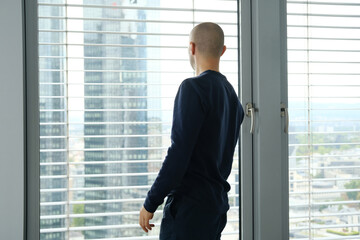 young man stands in an office in front of a window, looks at a modern European city, the concept of a business idea, a workplace