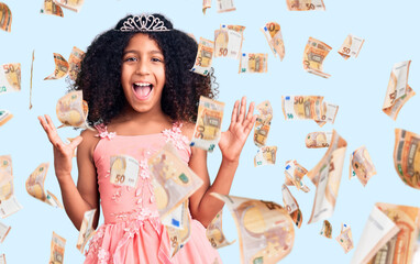 African american child with curly hair wearing princess crown celebrating victory with happy smile...
