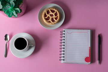 Naklejka premium Mesa de escritorio de oficina con cuaderno y lapicera y una taza de café. Vista superior.