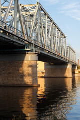 Metal truss railway bridge across the river on stone supports.