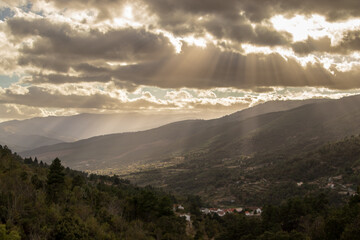 Obraz na płótnie Canvas fantastic mountain landscape, with the sun's rays radiating through the cloudy sky, creating a fantastic scenery , Serra da Estrela , Portugal
