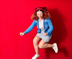 Young beautiful latin woman wearing casual clothes smiling happy. Jumping with smile on face doing winner gesture with fists up over isolated red background