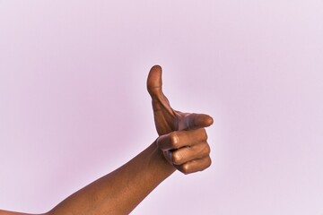 Arm and hand of black middle age woman over pink isolated background pointing forefinger to the camera, choosing and indicating towards direction