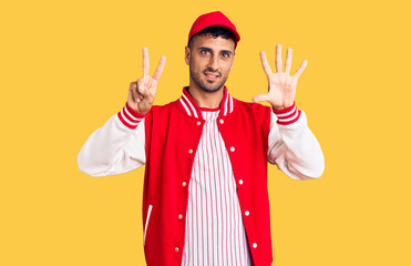 Young hispanic man wearing baseball uniform showing and pointing up with fingers number seven while smiling confident and happy.