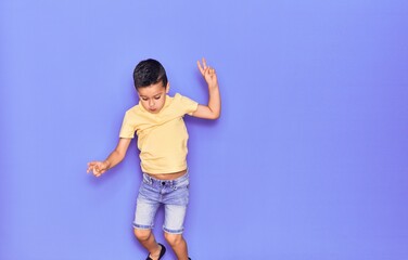 Adorable kid wearing casual clothes jumping over isolated purple background