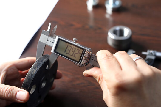The worker is measuring to thickness of flange with digital vernier caliper gauge. Vernier calipers are widely used in scientific laboratories and in manufacturing for quality control measurements.