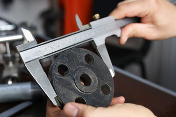 The worker is measuring to outer diameter of flange with vernier caliper gauge. Vernier calipers...
