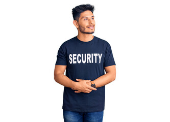 Handsome latin american young man wearing security t shirt smiling looking to the side and staring away thinking.