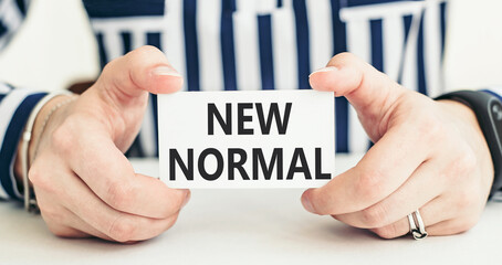 New normal concept effected by COVID 19 coronavirus that changes our lifestyle. Woman holding a card with a message text written on it