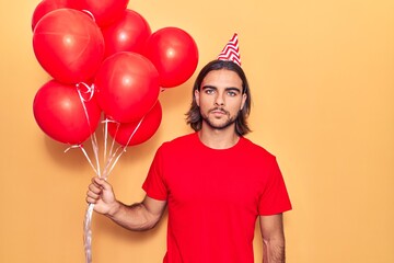 Fototapeta na wymiar Young handsome man holding balloons thinking attitude and sober expression looking self confident