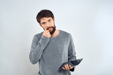 A bearded man with a tablet in his hands a gray jacket technology internet light background