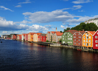 Naklejka premium View From Gamle Bybru Bridge To The Coloured Wooden Waterfront Of Bakklandet In Trondheim At The Nidelv River On A Sunny Summer Day With A Clear Blue Sky And A Few Clouds