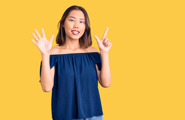 Young beautiful chinese girl wearing casual clothes showing and pointing up with fingers number seven while smiling confident and happy.