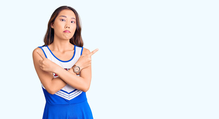 Young beautiful chinese girl wearing cheerleader uniform pointing to both sides with fingers,...