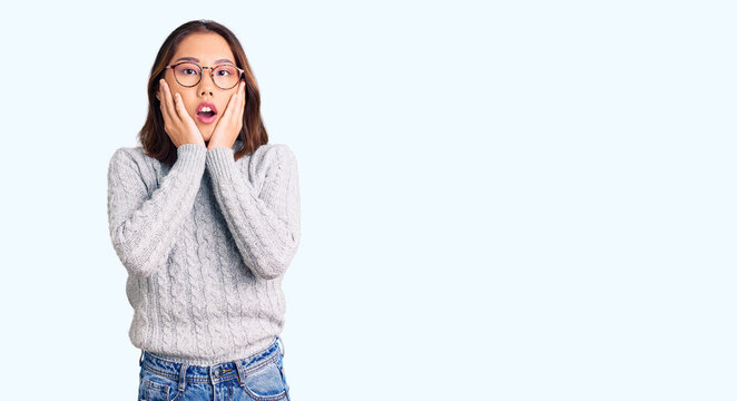 Young beautiful chinese girl wearing casual clothes afraid and shocked, surprise and amazed expression with hands on face