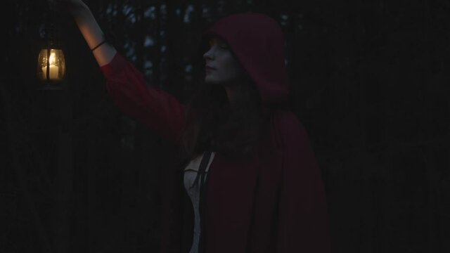Red riding hood in dark woods with lantern, slow motion