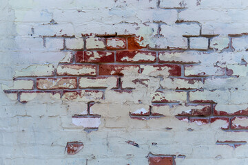 Red bricks show through old white paint