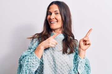 Young beautiful brunette woman wearing casual t-shirt standing over isolated white background smiling and looking at the camera pointing with two hands and fingers to the side.