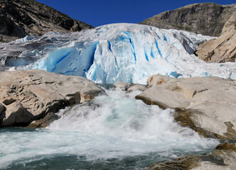 Water Splashing At The Bottom Of The Glacier Nigardsbreen In Jostedalsbreen National Park On A Sunny Summer Day With A Clear Blue Sky