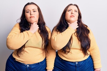 Young plus size twins wearing casual clothes touching painful neck, sore throat for flu, clod and infection